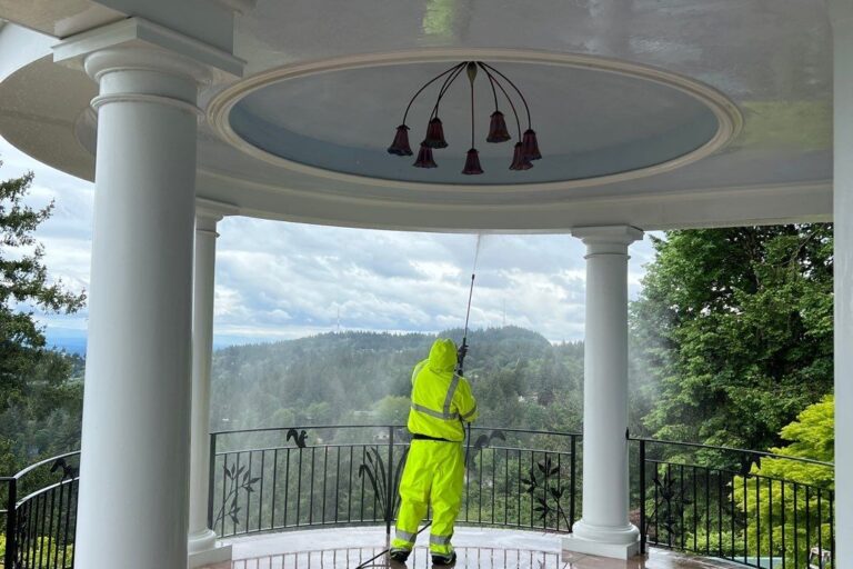 Sundeleaf Painting team member pressure washing a porch ceiling