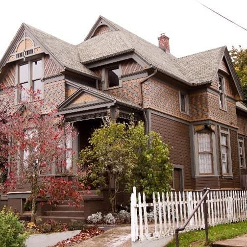 Older House With Brown Details And White Picket Fence