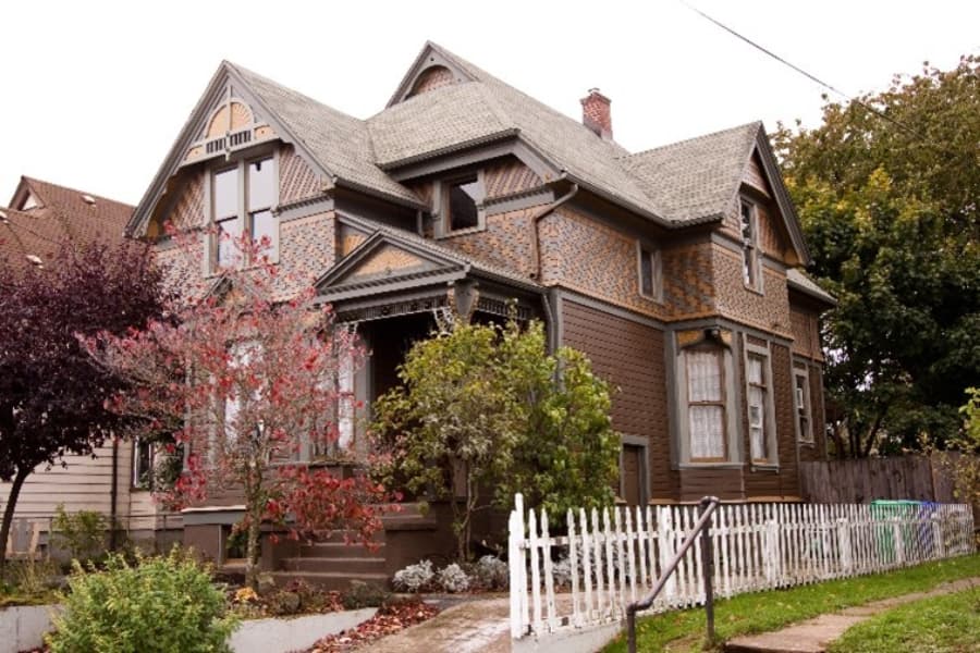 Older House With Brown Exterior And White Picket Fence