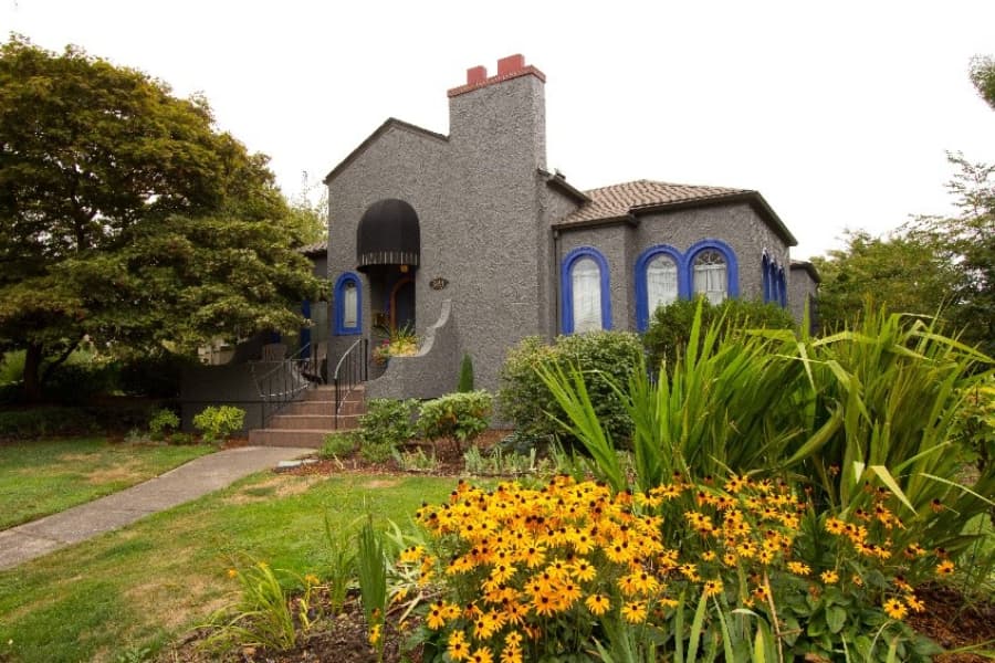 Gray House With Blue Trim And Flowers Out Front