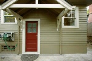 Covered Exterior Side Entrance Of Home With Bright Door