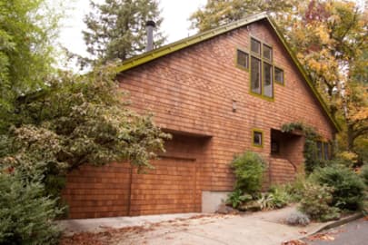 Stylish wooden garage with cross windows and lush greenery