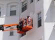 Painter On Lift Painting Side Of Commercial Building