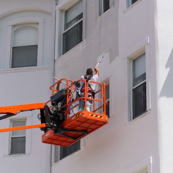 Painter On Lift Painting Side Of Commercial Building