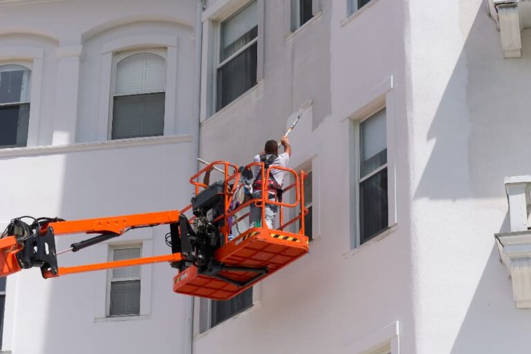 Painter On Lift Painting Side Of Commercial Building