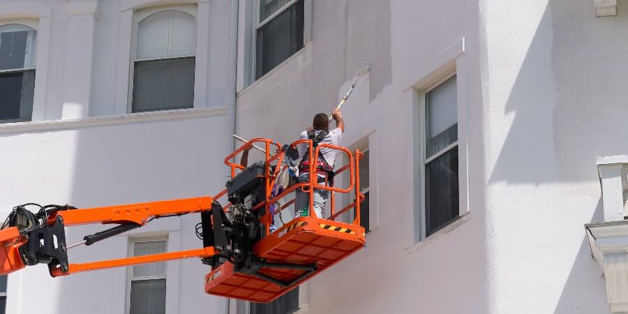 Painter On Lift Painting Side Of Commercial Building Painter On Lift Painting Side Of Commercial Building